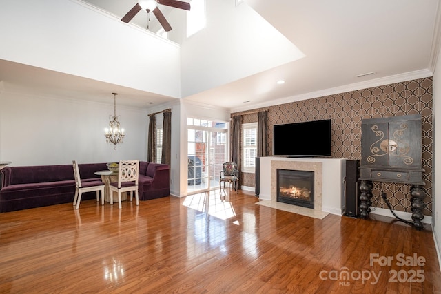 living room featuring a high end fireplace, ceiling fan with notable chandelier, and hardwood / wood-style floors