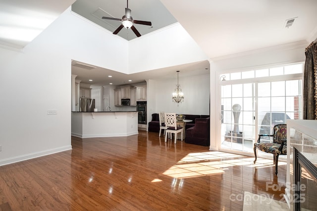 living room featuring a high ceiling, crown molding, ceiling fan with notable chandelier, and dark hardwood / wood-style floors