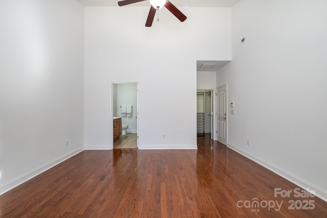 spare room featuring ceiling fan, dark hardwood / wood-style flooring, and a towering ceiling