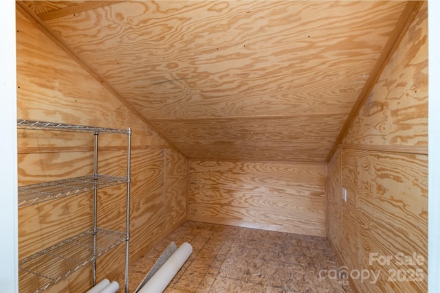 bonus room with vaulted ceiling and wood walls