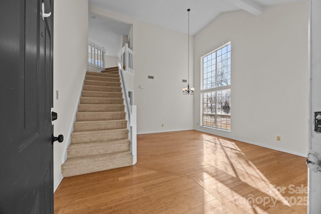 foyer featuring a notable chandelier, light hardwood / wood-style flooring, beam ceiling, and high vaulted ceiling