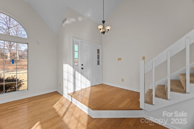 entrance foyer featuring high vaulted ceiling, hardwood / wood-style floors, and a notable chandelier