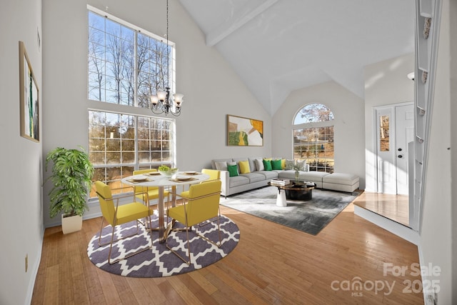 living room featuring high vaulted ceiling, wood-type flooring, beamed ceiling, and a notable chandelier