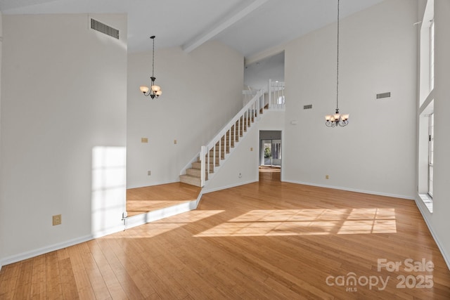 unfurnished living room featuring high vaulted ceiling, hardwood / wood-style floors, beam ceiling, and a notable chandelier