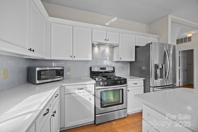 kitchen featuring white cabinets, light hardwood / wood-style flooring, appliances with stainless steel finishes, and tasteful backsplash