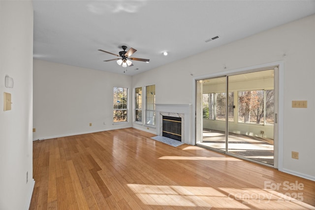 unfurnished living room featuring ceiling fan, light wood-type flooring, and a fireplace