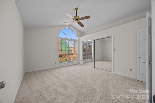 unfurnished bedroom with ceiling fan, light colored carpet, a closet, and vaulted ceiling