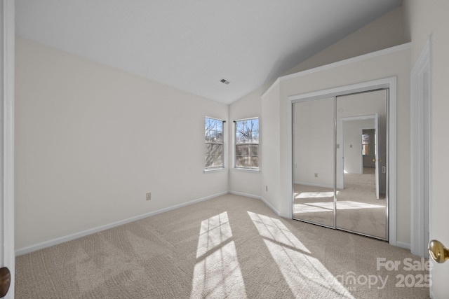 unfurnished bedroom with light colored carpet, a closet, and vaulted ceiling