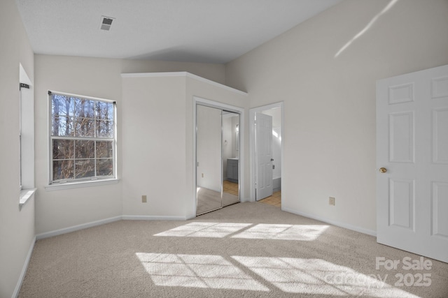 unfurnished bedroom with light colored carpet and lofted ceiling