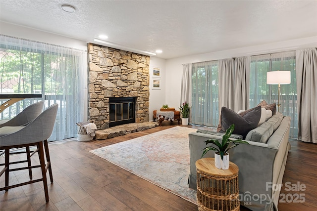 living room with a textured ceiling, plenty of natural light, a fireplace, and dark wood-type flooring