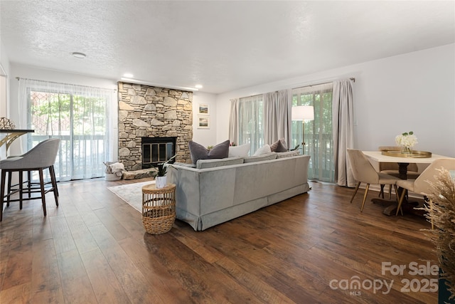 living room with dark hardwood / wood-style flooring, a fireplace, and a textured ceiling