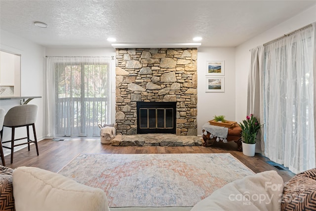 living room with hardwood / wood-style floors, a fireplace, and a textured ceiling