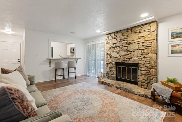 living room featuring a fireplace, a textured ceiling, and hardwood / wood-style flooring