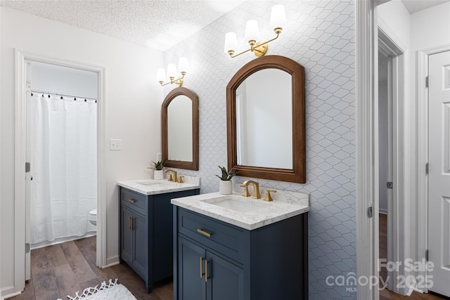 bathroom with hardwood / wood-style flooring, vanity, toilet, and a textured ceiling