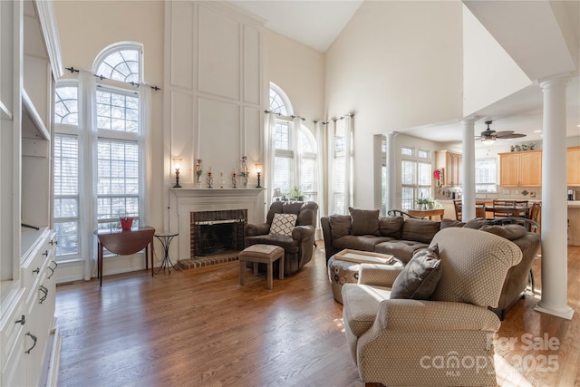 living room featuring a high ceiling, a brick fireplace, and ceiling fan