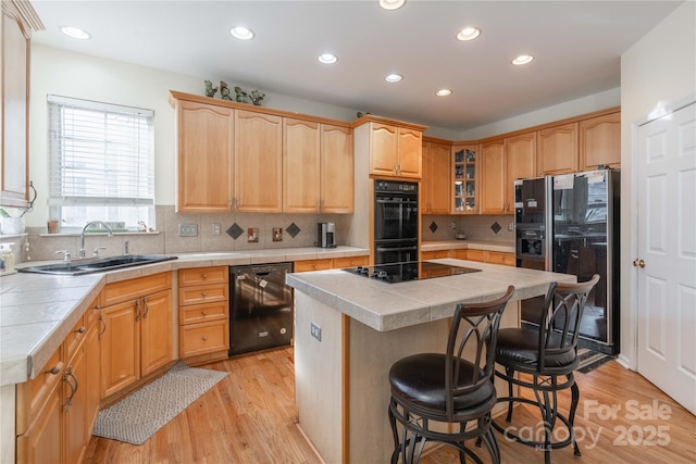 kitchen featuring sink, a center island, tile countertops, and black appliances