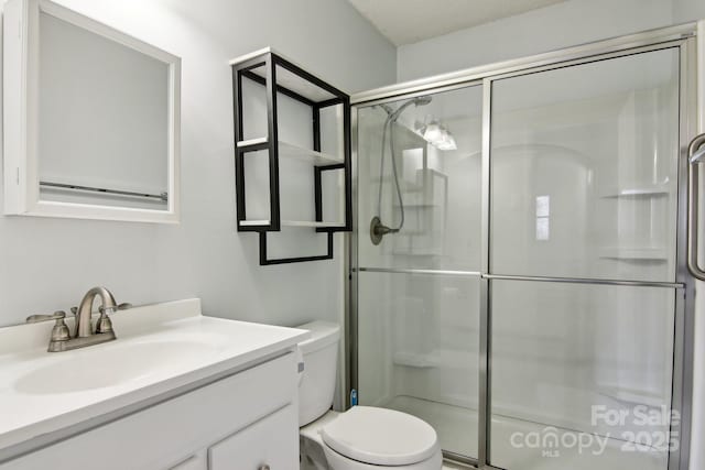 bathroom with toilet, a textured ceiling, walk in shower, and vanity