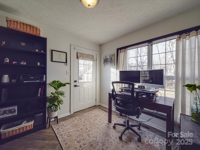 home office with a textured ceiling, baseboards, and wood finished floors