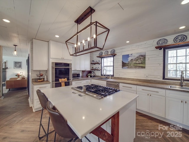 kitchen featuring open shelves, appliances with stainless steel finishes, a sink, and white cabinets