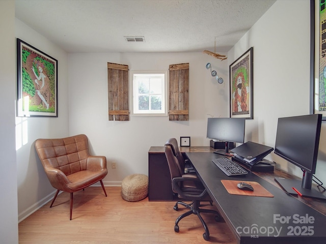 home office featuring baseboards, a textured ceiling, visible vents, and wood finished floors