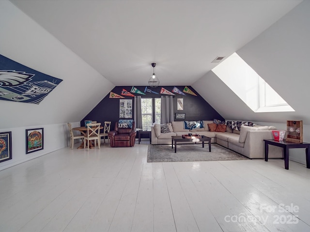 living area with lofted ceiling with skylight, hardwood / wood-style flooring, and visible vents