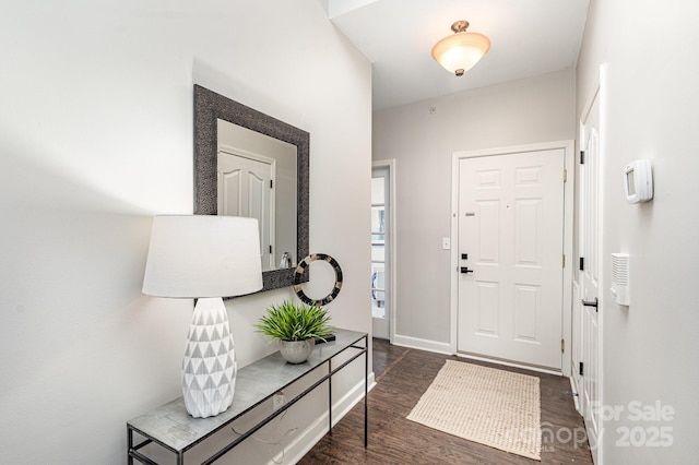 foyer with dark wood-type flooring and baseboards