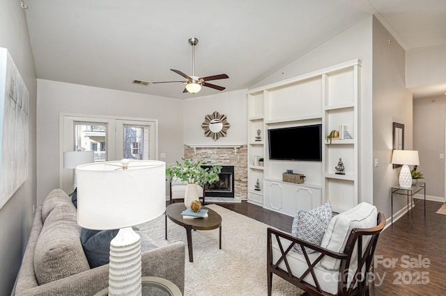 living room with visible vents, dark wood finished floors, a ceiling fan, vaulted ceiling, and a fireplace