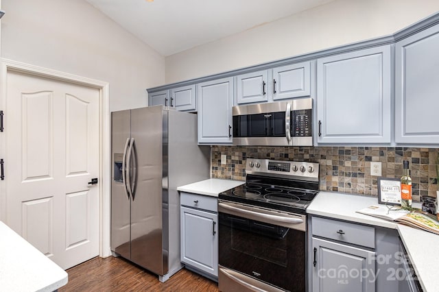 kitchen featuring dark wood-style floors, light countertops, backsplash, gray cabinetry, and appliances with stainless steel finishes