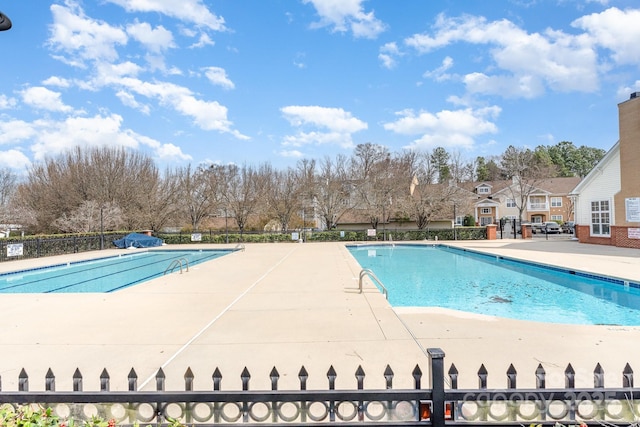 pool with a patio and fence