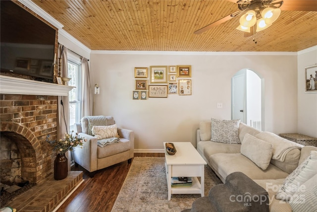 living room with wooden ceiling, a brick fireplace, ceiling fan, dark hardwood / wood-style floors, and crown molding