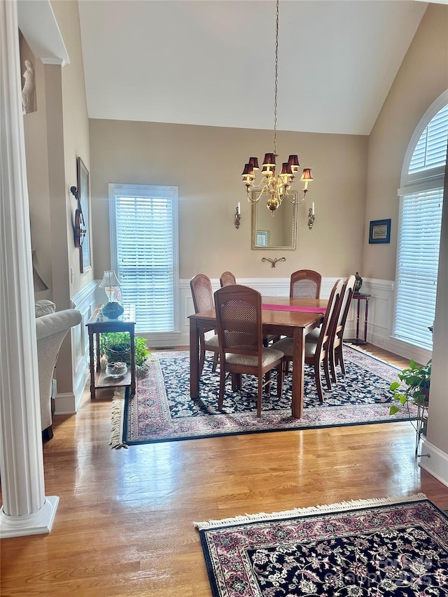 dining area with light wood-type flooring, vaulted ceiling, and a chandelier