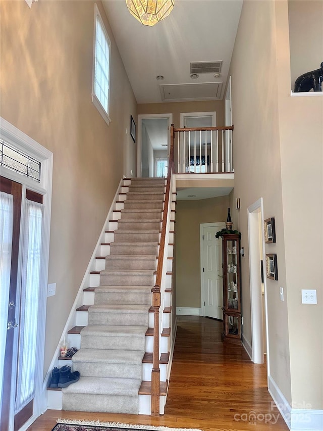 stairway with a towering ceiling and hardwood / wood-style floors