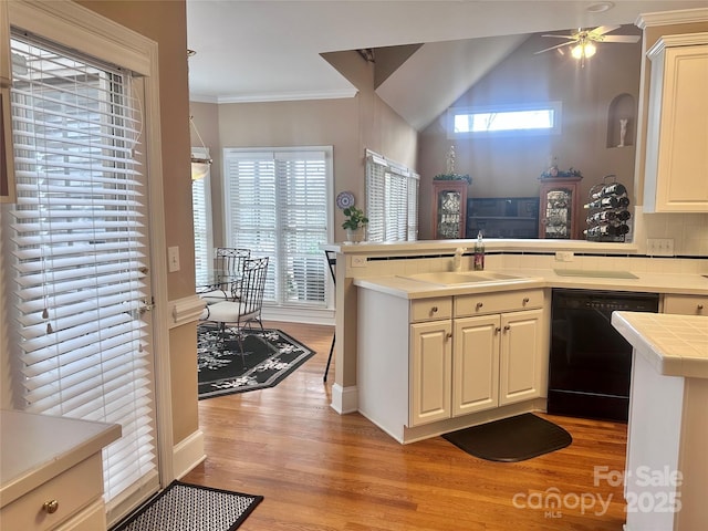 kitchen with kitchen peninsula, sink, black dishwasher, and light hardwood / wood-style flooring