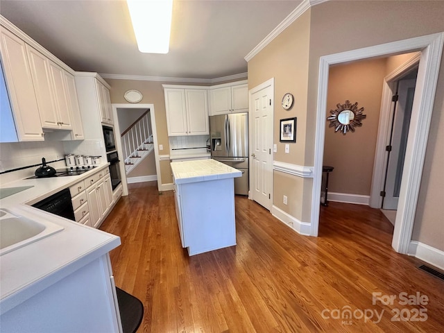 kitchen featuring decorative backsplash, white cabinets, black appliances, and a kitchen island