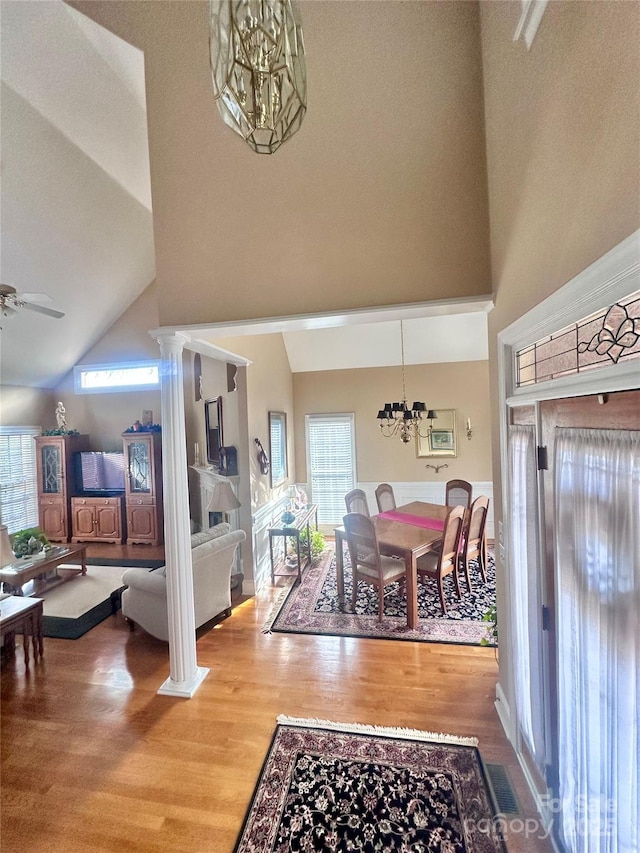 interior space featuring high vaulted ceiling, hardwood / wood-style flooring, ornate columns, and ceiling fan with notable chandelier