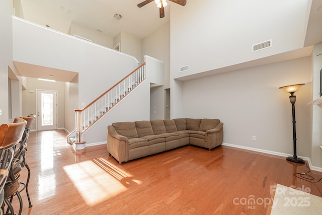 living room featuring hardwood / wood-style floors, ceiling fan, and a high ceiling