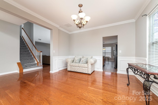 sitting room featuring hardwood / wood-style floors, an inviting chandelier, plenty of natural light, and crown molding