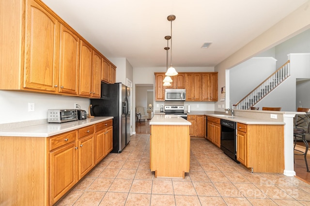 kitchen featuring kitchen peninsula, pendant lighting, a breakfast bar, a kitchen island, and appliances with stainless steel finishes