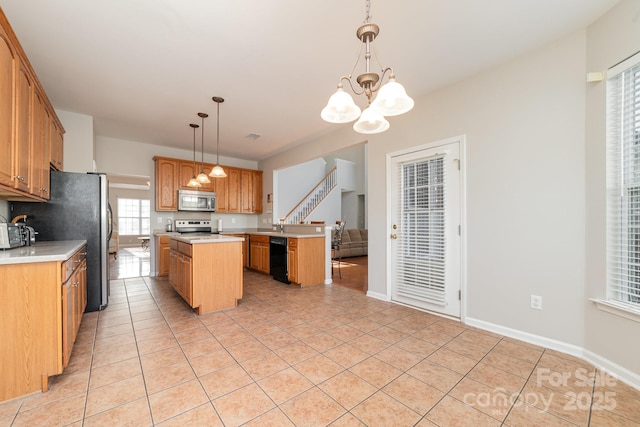 kitchen featuring appliances with stainless steel finishes, pendant lighting, a notable chandelier, a kitchen island, and light tile patterned flooring