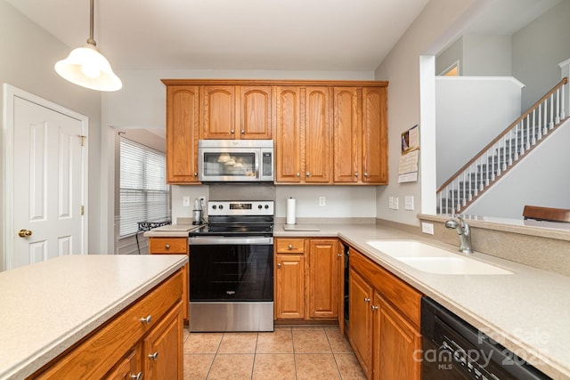 kitchen with hanging light fixtures, sink, light tile patterned flooring, and stainless steel appliances