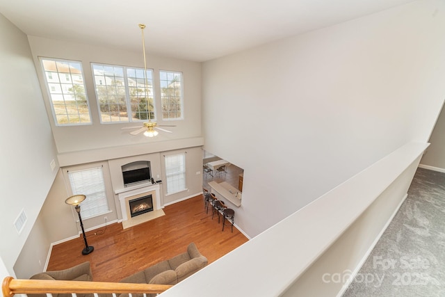 living room with hardwood / wood-style floors, ceiling fan, and a high ceiling