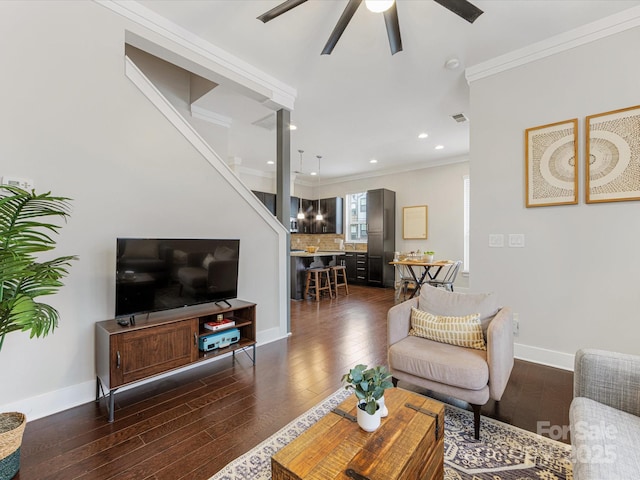 living room with dark wood-type flooring, ornamental molding, and ceiling fan