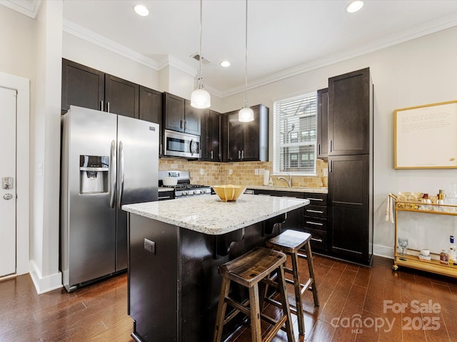 kitchen with pendant lighting, a breakfast bar, appliances with stainless steel finishes, a center island, and dark brown cabinetry