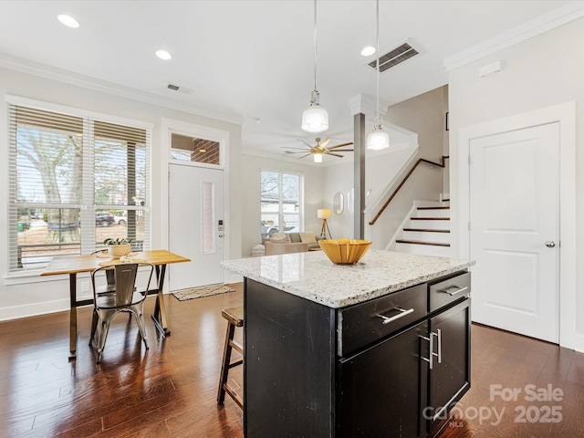 kitchen with pendant lighting, ornamental molding, a breakfast bar area, and a kitchen island