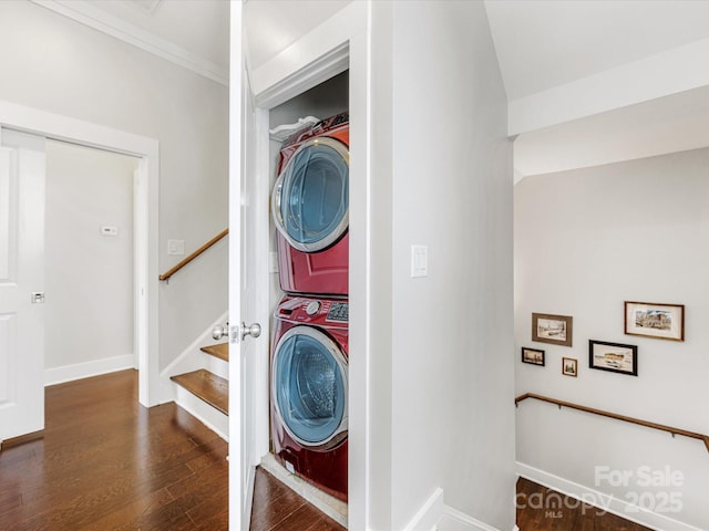 laundry area with crown molding, stacked washer and clothes dryer, and dark hardwood / wood-style flooring