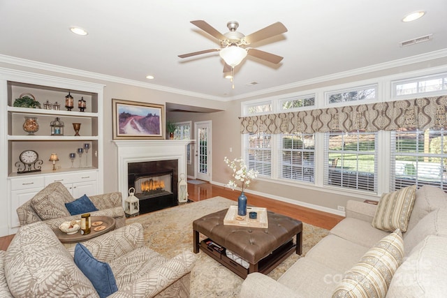 living room featuring crown molding, light wood-type flooring, and a wealth of natural light