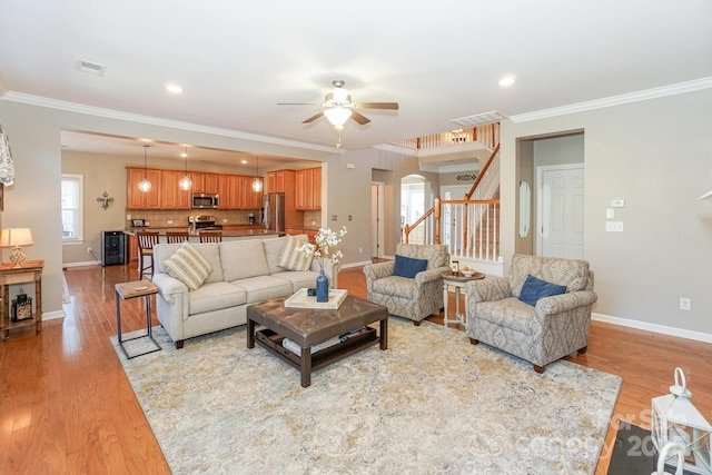 living room featuring ceiling fan, light hardwood / wood-style flooring, and crown molding