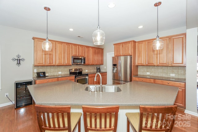 kitchen with stainless steel appliances, wine cooler, and an island with sink