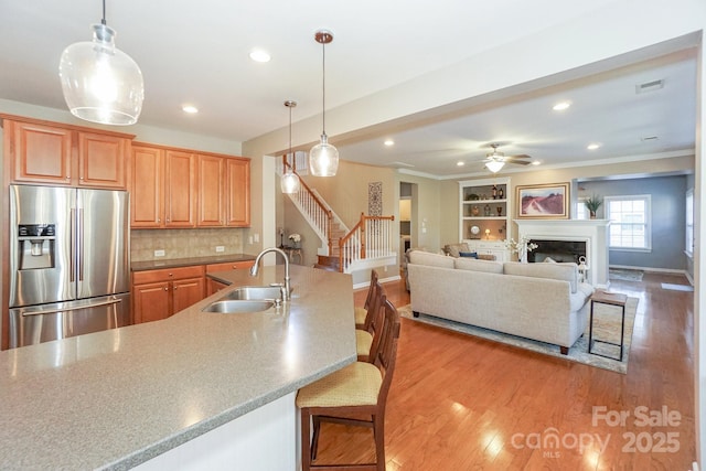 kitchen featuring sink, hanging light fixtures, a breakfast bar, and stainless steel refrigerator with ice dispenser