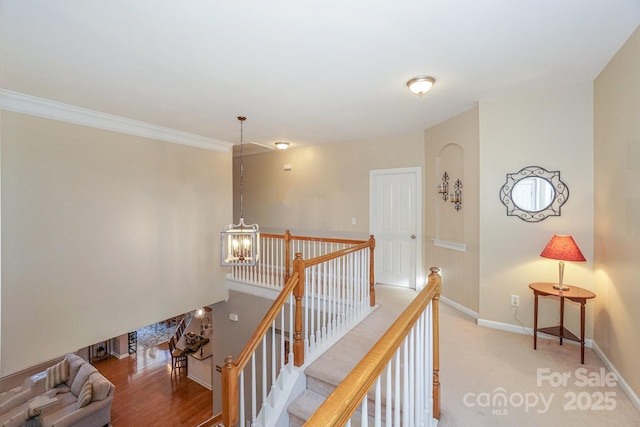 hall with a notable chandelier, crown molding, and light carpet